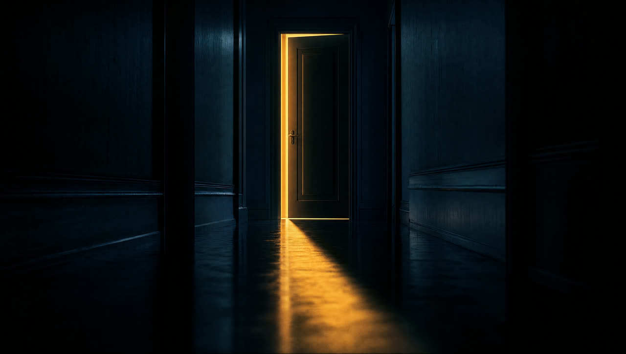 A door ajar with warm light spilling into a dark hallway